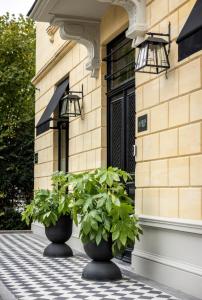 Dos plantas en jarrones negros en el frente de un edificio. en Villa V Petit Hôtel, en Valkenburg 44 fotos más