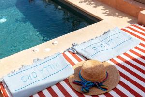 a hat and two towels on a table next to a swimming pool at Villa Oro in Oia +39 photos
