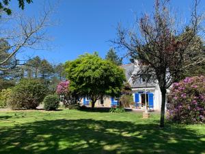 a house with a green yard with trees and flowers at La Gentilhommière in Tréffiagat +7 photos