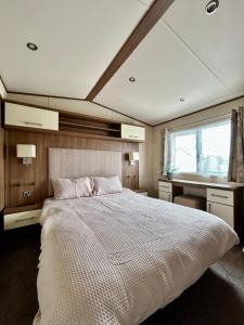 a bedroom with a large white bed and a window at VerbLake 5 Berth Caravan St Osyth Beach Holiday Park in Saint Osyth