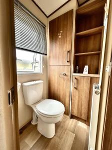 a small bathroom with a toilet and a window at VerbLake 5 Berth Caravan St Osyth Beach Holiday Park in Saint Osyth