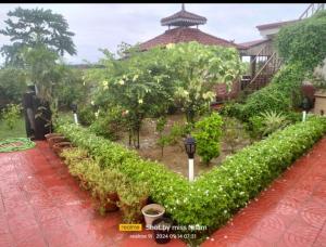 a garden with bushes and trees and a building at Kheya Kutir in Shānti Niketan