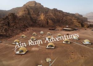 a group of tents in a desert with a mountain at مغامرات عين رم in Wadi Rum