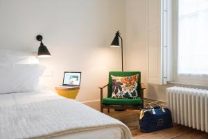 a bedroom with a bed and a green chair at Hotel des Galeries in Brussels