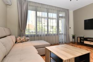 Una sala de estar con un sofá y una ventana grande. en Апартамент Инфинити, en Veliko Tŭrnovo