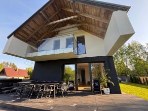 a modern house with a balcony with a table and chairs at Enklawa Winiec - nowoczesny dom nad jeziorem, 6 sypialni, jacuzzi in Winiec