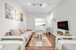 a white living room with a couch and a tv at "Olive & Bloom" entire vila with Pool & Private Parking in Berat