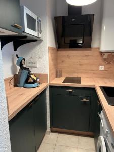 a kitchen with green cabinets and a microwave at Le Maya in Sainte-Maxime
