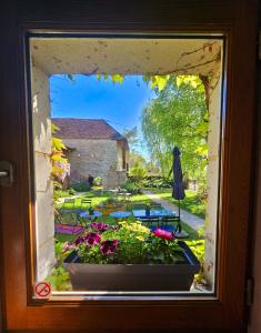 una finestra con vista su un giardino esterno di La Ferme du Cerf Bleu a Sanvigné