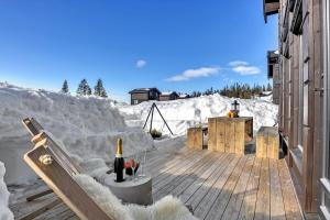 eine Terrasse im Schnee mit einer Flasche Wein in der Unterkunft New, cozy cottage on Norefjell with stunning views in Noresund + 15 Fotos