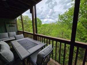 een afgeschermde veranda met een tafel en stoelen bij Swan's Woodland Getaway Condo in Reeds Spring