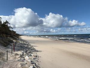 a beach with rocks and the ocean on a cloudy day at Apartament Bike & Baltic - 2 rowery w cenie in Koszalin