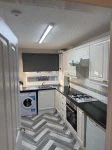 a kitchen with white cabinets and a black counter top at 2-Bed City Apartment by Glasgow Green in Glasgow