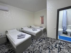 una habitación con dos camas y un baño con WC en Berkat Boutique, en Bukhara
