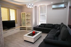 a living room with a black couch and a tv at Dream House Apartment in Durrës