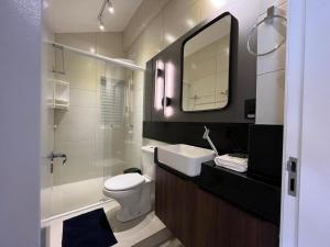 a bathroom with a toilet and a sink and a mirror at Loft Dona Clara 203 no Centro de Pomerode in Pomerode