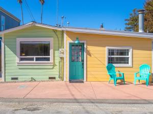 a green and yellow house with two blue chairs at Cottage at the Point - For 4 in Santa Cruz