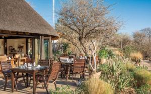 a restaurant with tables and chairs and a thatch roof at Immanuel Wilderness Lodge in Windhoek