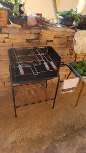 a grill with tongs and a bowl of fruit at Portais São Thomé casa de temporada in São Thomé das Letras