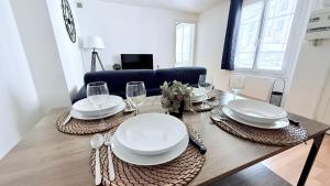 a dining room table with plates and wine glasses at Le Roy Soleil Classé 3 étoiles Cosy & Cœur du quartier Saint-Louis in Versailles +10 photos