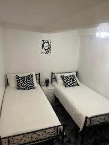 Forest HillにあるCozy Two Bedroom Flat 1 Minute from Forest Hill Train Stationの部屋に並んで置かれた2つのベッド