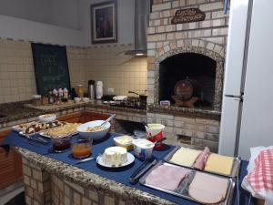 a kitchen with a table with food and a fireplace at Pousada Bonatti in Blumenau