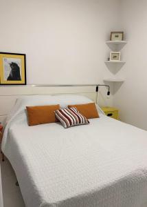 a white bed with two pillows on top of it at Quarto e Sala Temporada no Rio Vermelho in Salvador