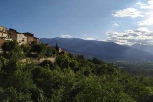 a village on a hill with trees and mountains at B&B Il Belvedere in Pacentro