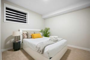 a white bedroom with a white bed and a window at Modern 2BR Private Suite NW Near Airport & Amazing Shopping! Free Banff Pass, Netflix, Parking! in Calgary +25 photos