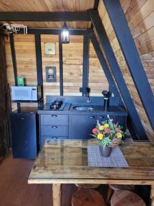 a kitchen with a stove and a table with flowers on it at Chalé Encanto Do Lago in Urubici