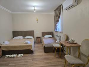 una habitación de hotel con dos camas y una mesa en Golden Time, en Almaty