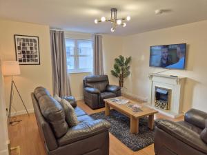 a living room with leather furniture and a fireplace at Spacious Modern 2-BR Apartment in Aberdeen City Centre in Aberdeen