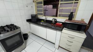 a small kitchen with a sink and a microwave at Casa da Sementes in Uberlândia +2 photos