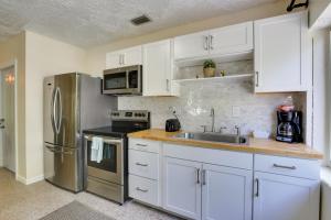 a kitchen with white cabinets and a stainless steel refrigerator at Walk to Ocean Chic Deerfield Beach Cottage! in Deerfield Beach +27 photos