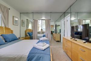 a bedroom with a large bed and a mirror at Walk to Ocean Chic Deerfield Beach Cottage! in Deerfield Beach