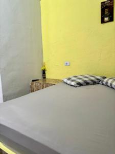 uma cama grande em um quarto com uma parede amarela em Kitnet Aconchegante Simples e Bem Localizada em Serra Negra