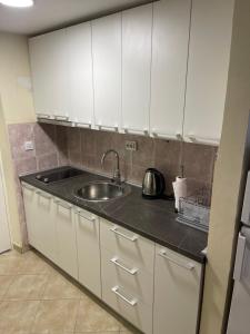 a kitchen with a sink and white cabinets at Becici Apart Budva in Budva +2 photos