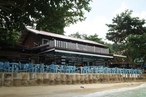 a building with blue chairs on the beach at The Barat Perhentian in Perhentian Islands
