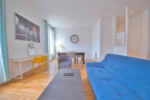 een woonkamer met een blauwe bank en een tafel bij Papeete 3 bedrooms in Reims
