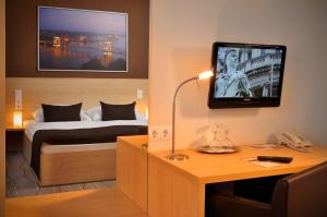 a hotel room with a bed and a tv on the wall at Promenade City Hotel in Budapest