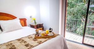 a bedroom with a bed with a tray of food on it at Hotel Casa Laureles in Medellín