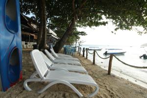 a row of white chairs sitting on a beach at The Barat Perhentian in Perhentian Islands