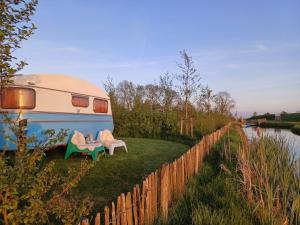 un camper parcheggiato accanto a una recinzione vicino a un fiume di Retro caravan de Duif vlakbij het Sneekermeer a Terzool
