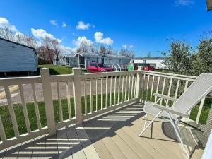 a deck with two chairs and a fence at Beautiful Caravan With Decking At California Cliffs In Scratby Ref 50052L in Great Yarmouth
