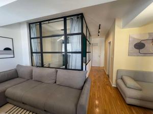 a living room with a couch and a large window at Gigi Apartment by eluxory in Skopje