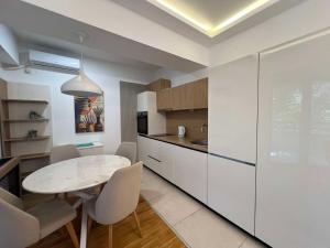 a kitchen with a table and white cabinets at Gigi Apartment by eluxory in Skopje