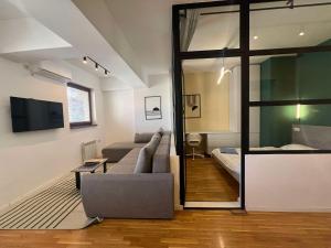 a living room with a couch and a bed and a mirror at Gigi Apartment by eluxory in Skopje