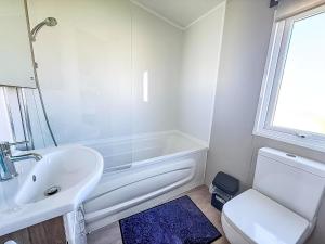 a bathroom with a sink and a tub and a toilet at Beautiful Caravan With Decking At California Cliffs In Scratby Ref 50052L in Great Yarmouth +12 photos