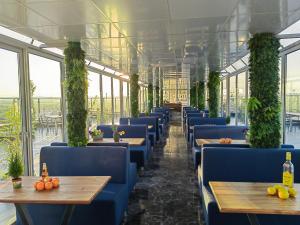 a restaurant with blue chairs and tables and windows at Rovno Hotel in Vidin