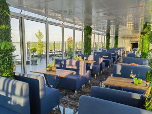 a restaurant with blue chairs and tables and windows at Rovno Hotel in Vidin